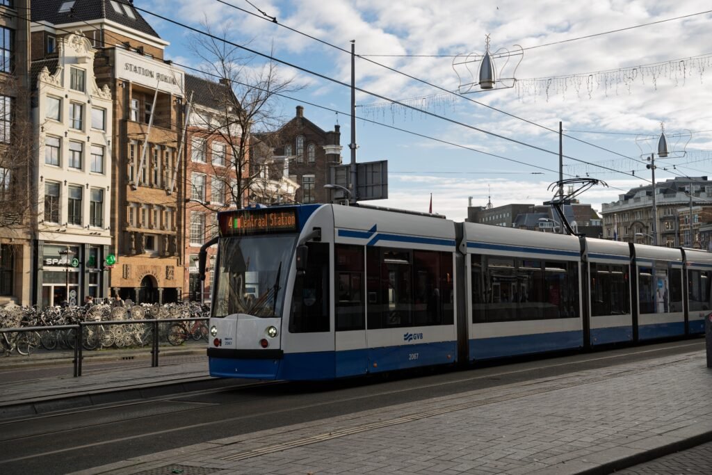 Tram in front of Centraal Station, Amsterdam, showcasing urban architecture and public transport.